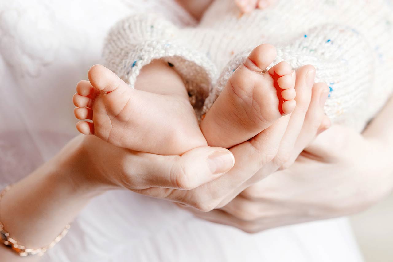 Photo of a tiny Newborn Baby's feet on female Heart Shaped hands