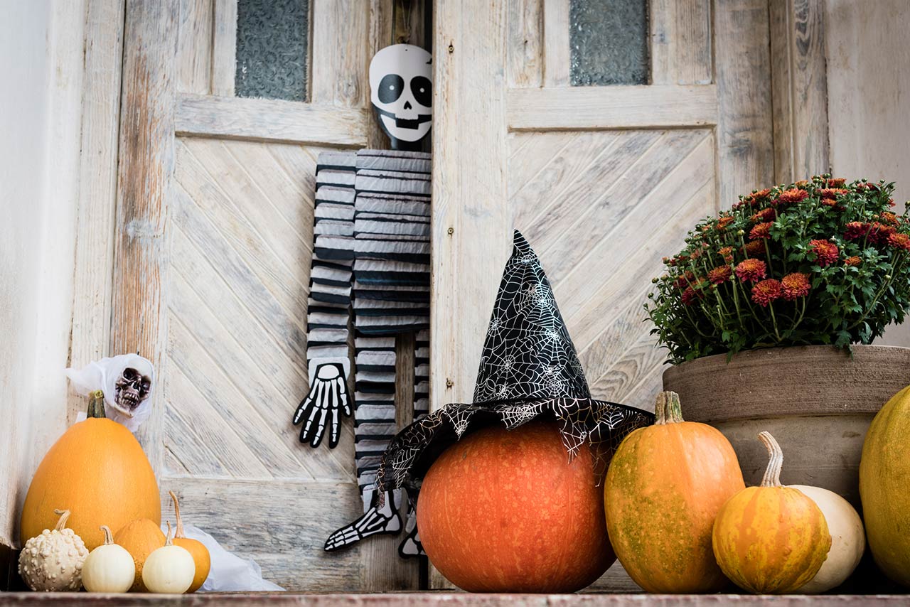 Halloween decorated front door with various size and shape pumpkins and skeletons